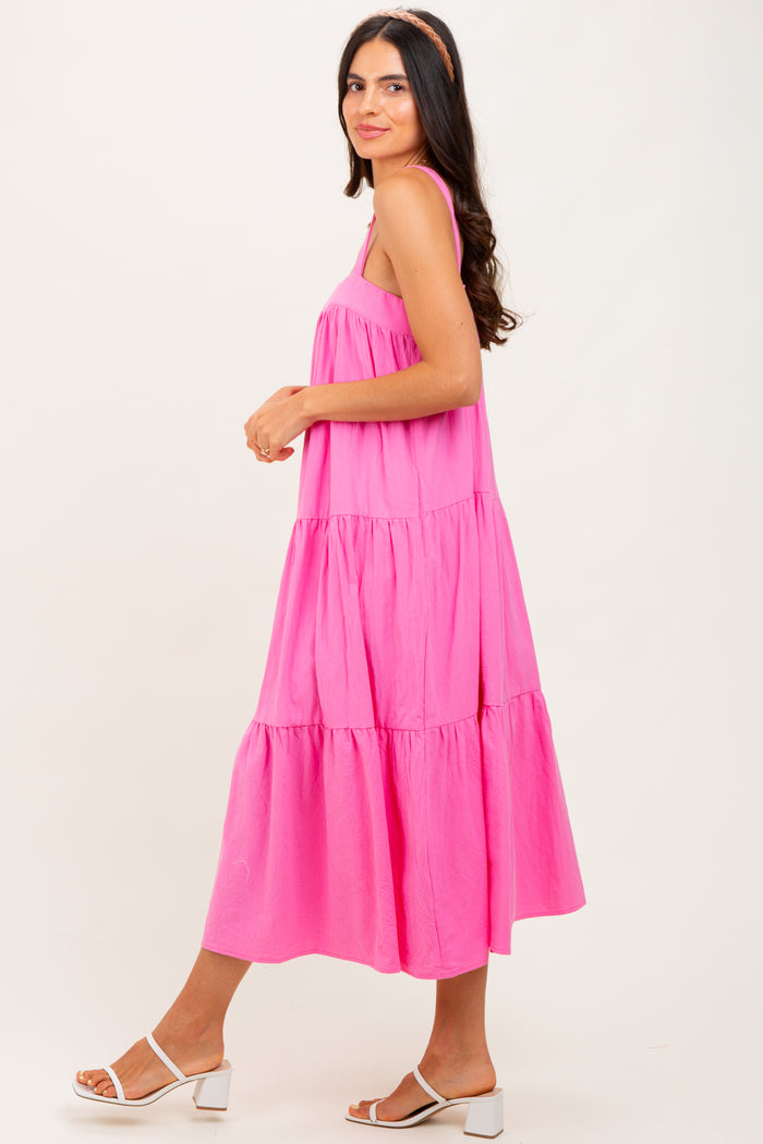 woman wearing a bright pink tiered midi dress with a loose fit and adjustable straps