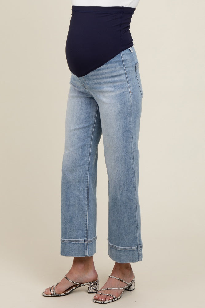 woman wearing light blue maternity jeans with a dark blue belly band and showing her baby bump