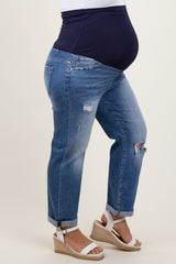 woman wearing light blue distressed maternity plus jeans and a navy top, showcasing a visible baby bump