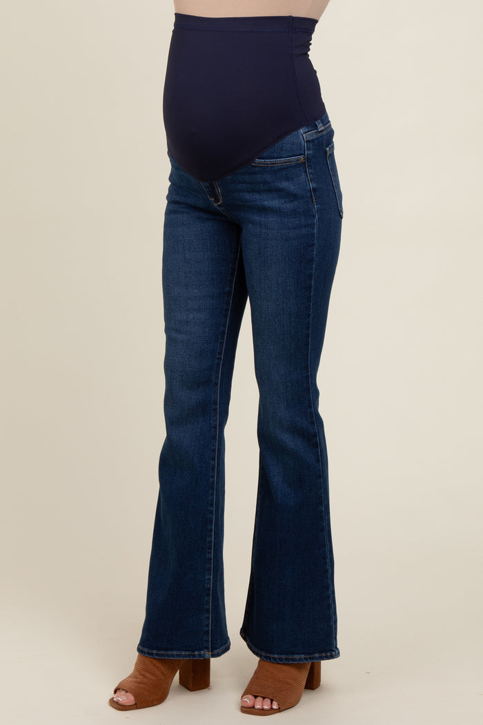 woman wearing dark blue flared maternity jeans with a supportive belly band and a visible baby bump
