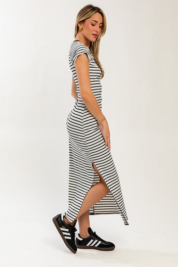 woman wearing a black and white striped maxi dress with side slits and paired with black sneakers