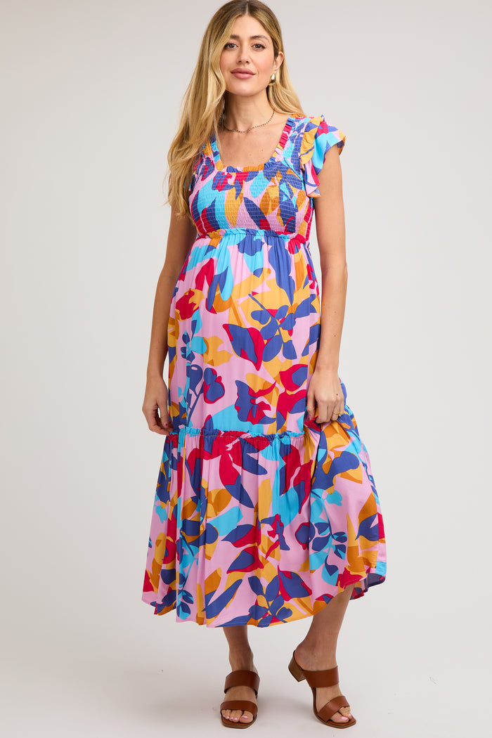 woman wearing a colorful floral maternity maxi dress with ruffle sleeves and a tiered skirt, showing her baby bump