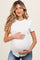 woman wearing a white short sleeve maternity top and holding her baby bump