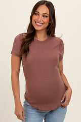 woman wearing a rust short sleeve ribbed maternity top and showing her baby bump