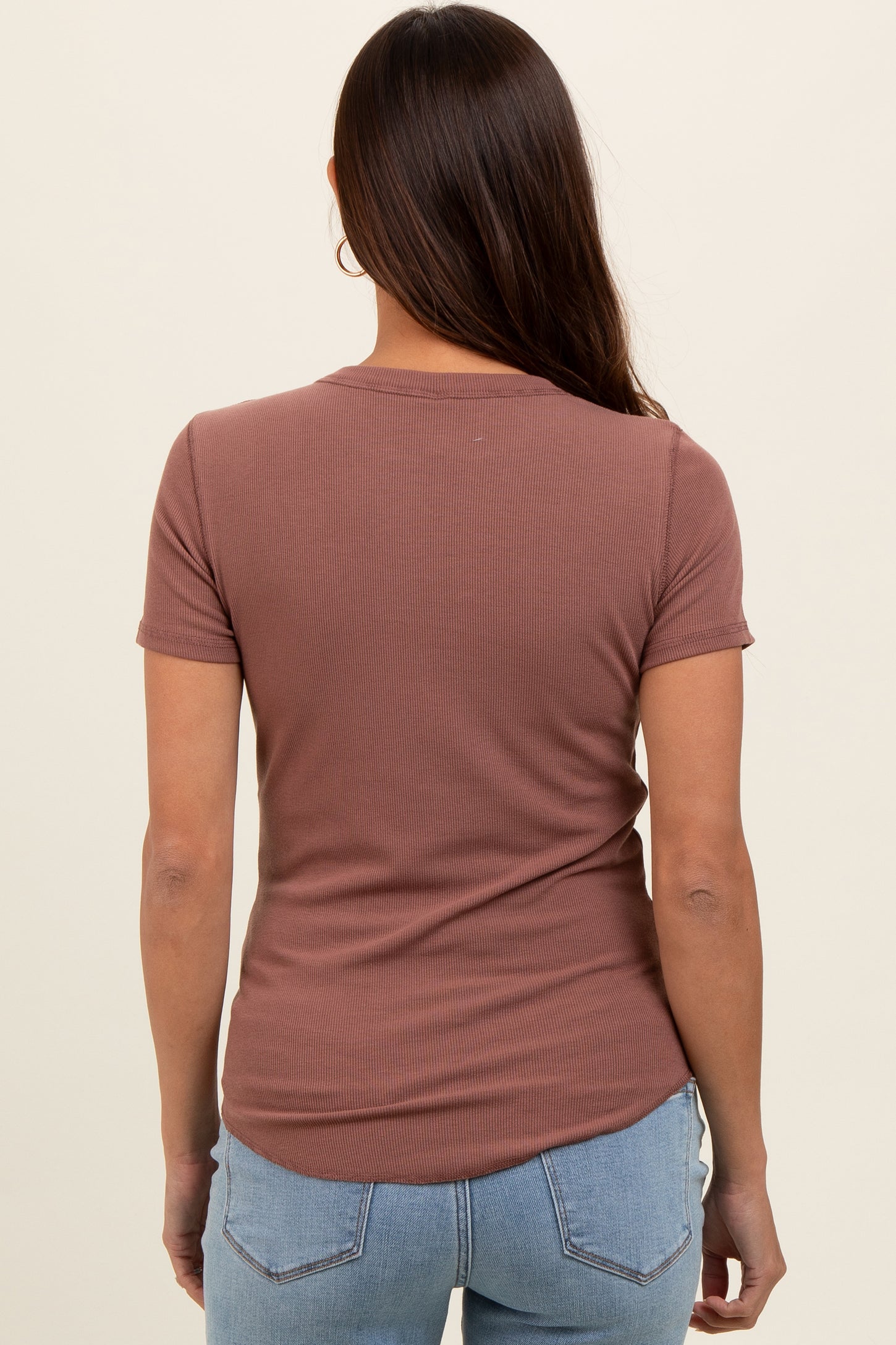 woman wearing a mauve short sleeve ribbed maternity top, seen from the back, with light blue jeans