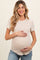 woman wearing a beige ribbed maternity top and holding her baby bump