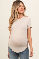 woman wearing a beige short sleeve maternity top, showing her baby bump, paired with distressed blue jeans
