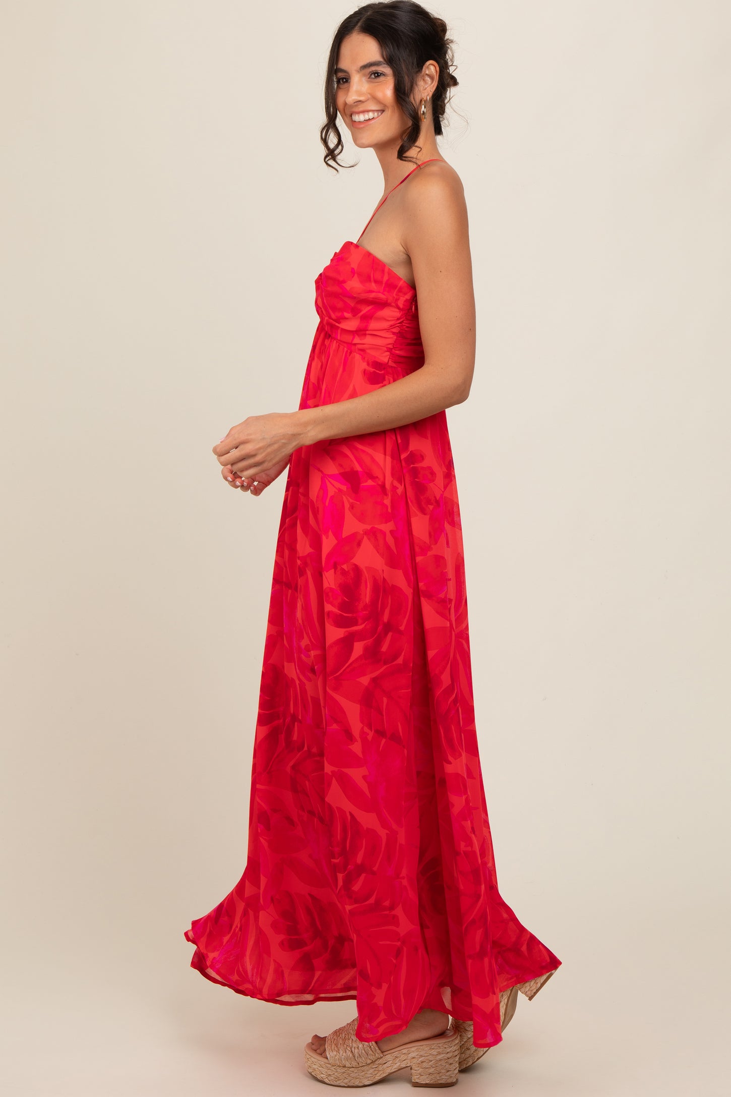 woman wearing a vibrant red floral maxi dress with a ruched bodice and spaghetti straps