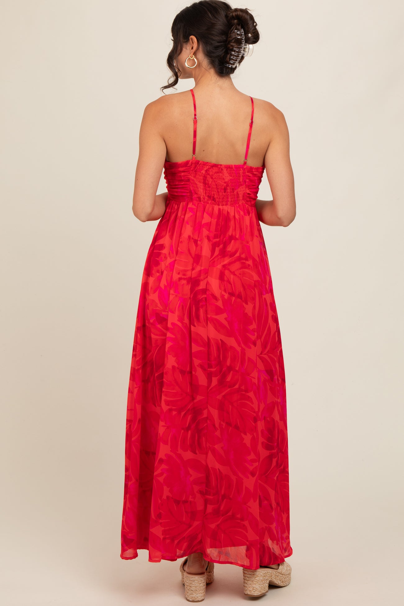 woman wearing a pink floral maxi dress with a smocked bodice and spaghetti straps, viewed from the back
