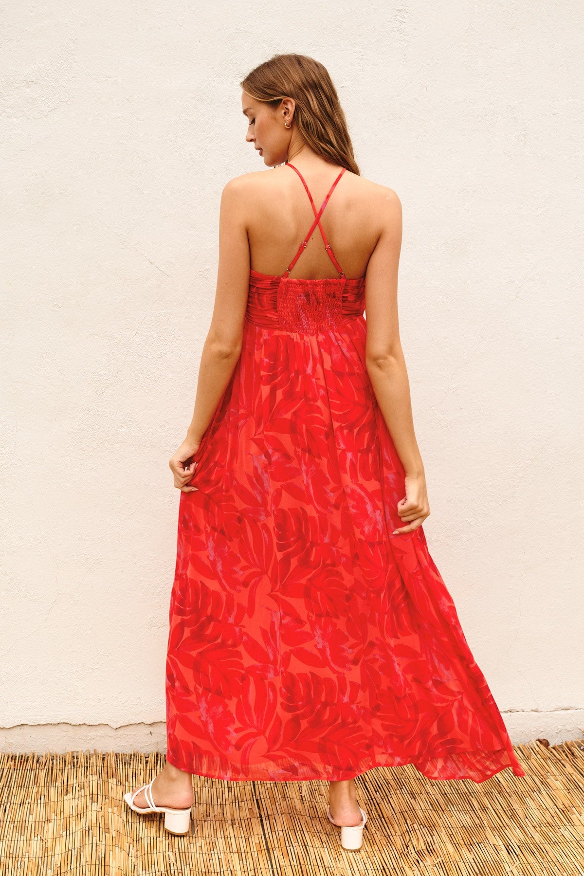 woman wearing a long red floral maxi dress with a strappy back design and a flowing silhouette