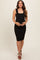 woman wearing a black ribbed maternity dress with a square neckline and a fitted silhouette, holding her baby bump