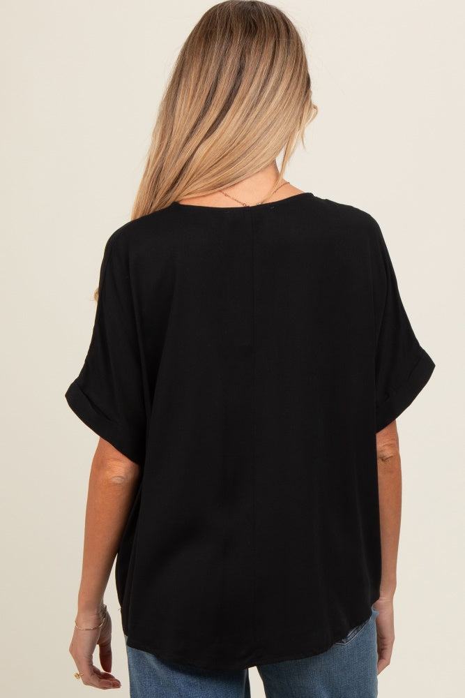 woman wearing a black short sleeve maternity top from the back, styled with rolled sleeves