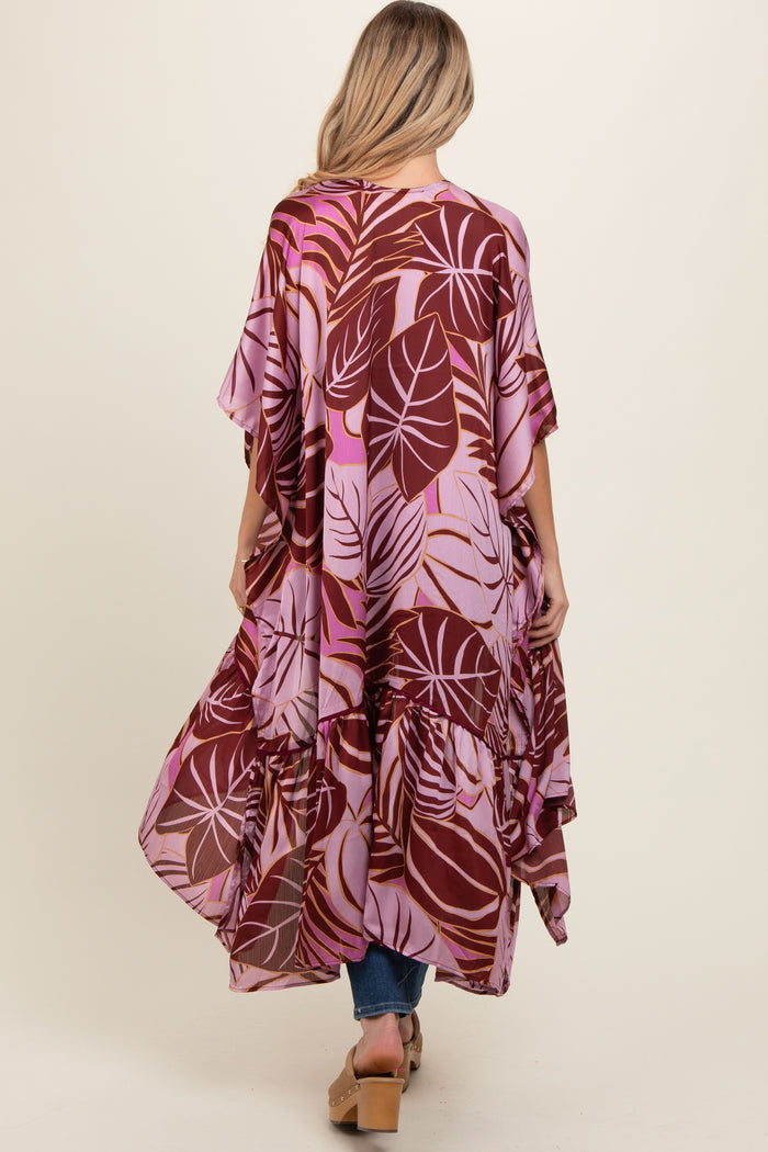 woman wearing a pink and burgundy leaf print maternity cover-up with a flowy design and ruffled hem