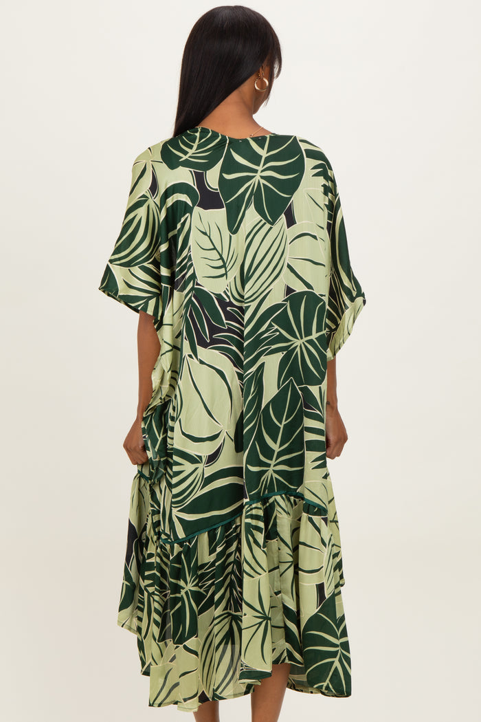woman wearing a green tropical leaf print tiered dress with short sleeves from the back