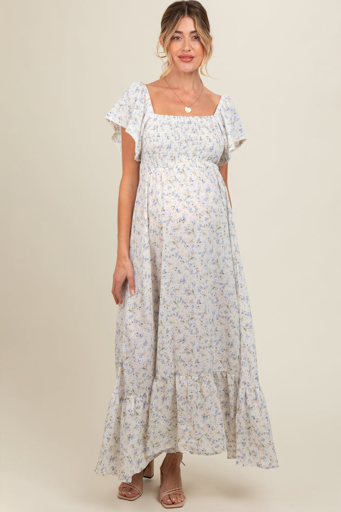 woman wearing a light blue floral maternity maxi dress with ruffled sleeves and a visible baby bump