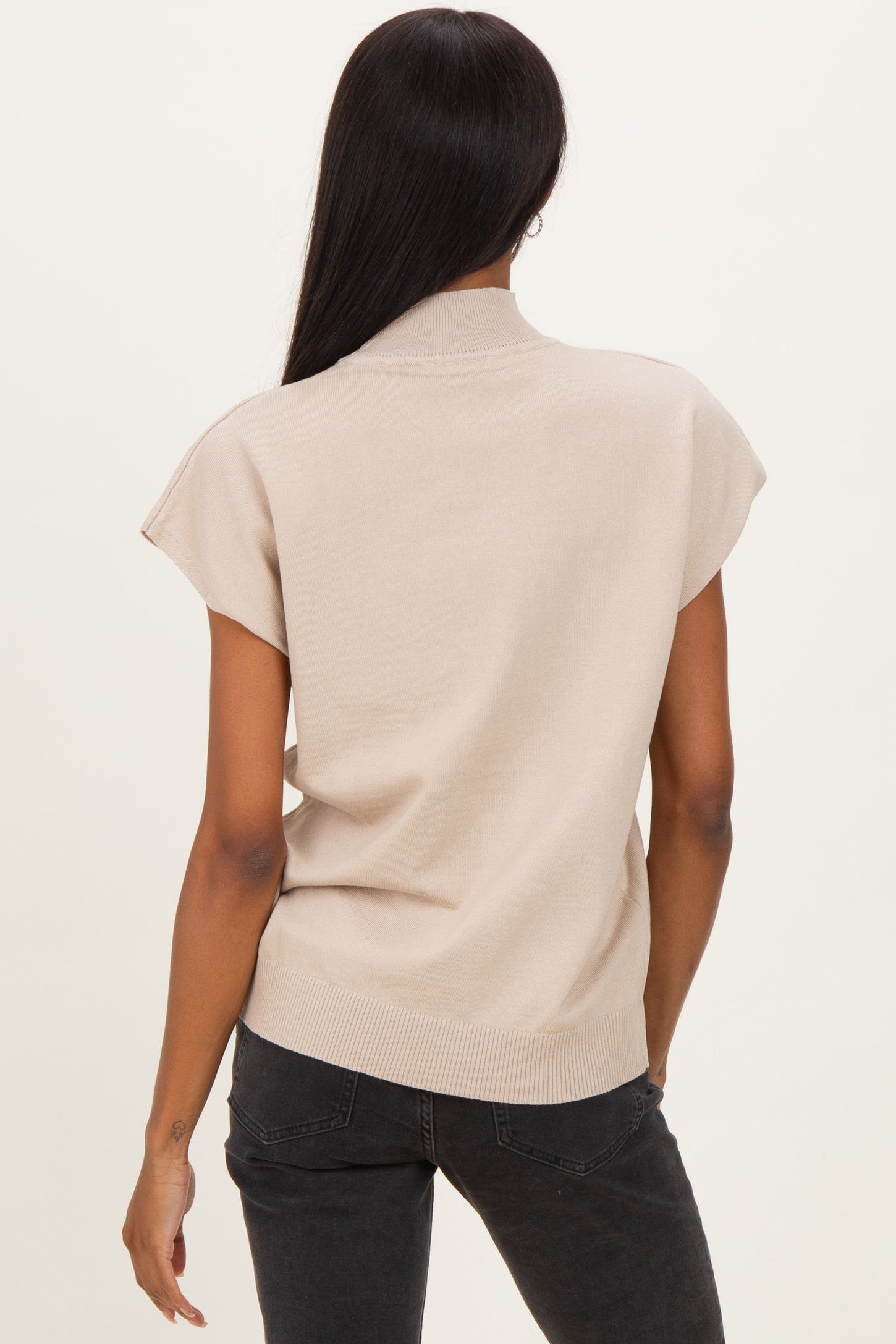 woman wearing a beige short sleeve sweater with a high neckline and a relaxed fit, viewed from the back