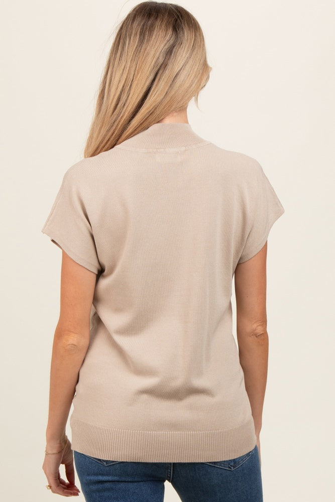 woman wearing a beige short sleeve maternity top, visible back view
