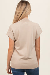 woman wearing a beige short sleeve maternity top, visible back view
