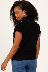 woman wearing a black short sleeve sweater with a ribbed hem and back detail, styled with high-waisted jeans