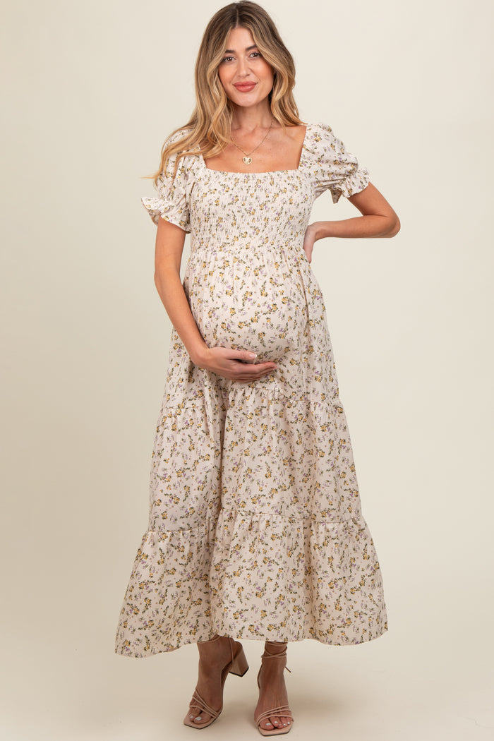 woman wearing a floral maternity dress with puff sleeves and tiered skirt, showing her baby bump
