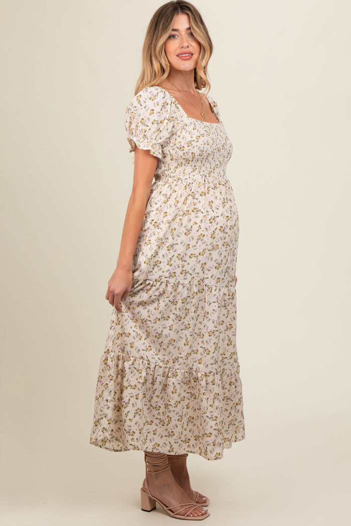 woman wearing a cream floral maternity maxi dress with puff sleeves and a fitted bodice, showing her baby bump
