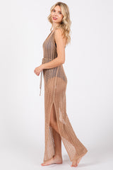 woman wearing a tan crochet maxi cover-up with side slits and a tie waist, standing in profile