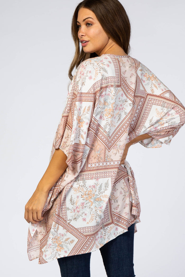 woman wearing a patterned maternity tunic with a loose fit and tied back detail, styled with dark jeans