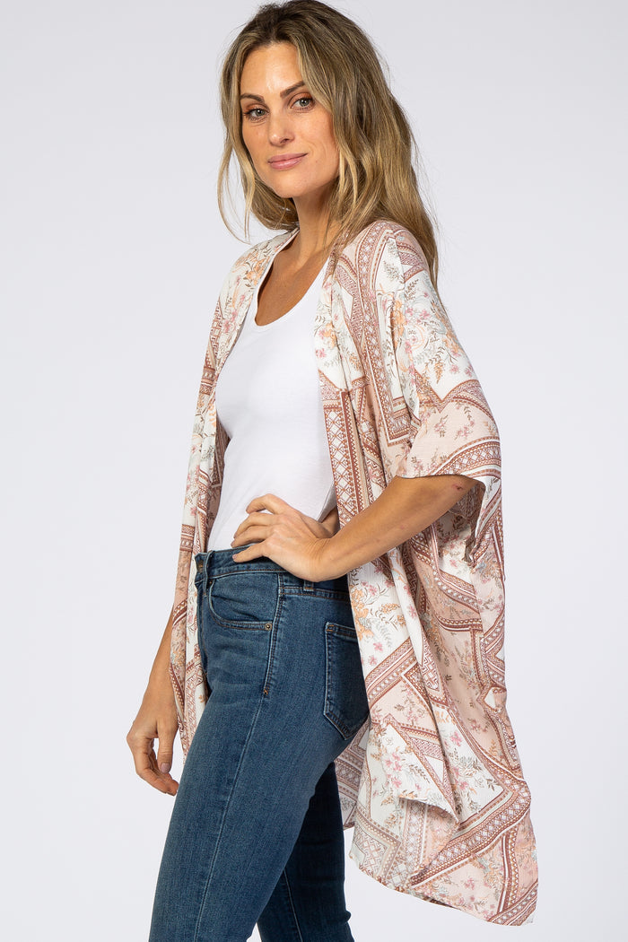 woman wearing a floral printed kimono over a white top and paired with skinny jeans