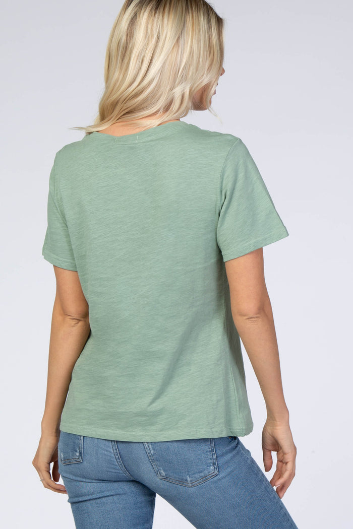 Back view of a woman with blonde hair wearing a sage green short sleeve t-shirt and blue jeans