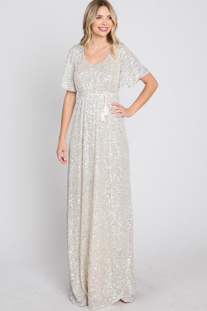 woman wearing a glamorous silver sequin maxi dress with short sleeves and a tie waist detail