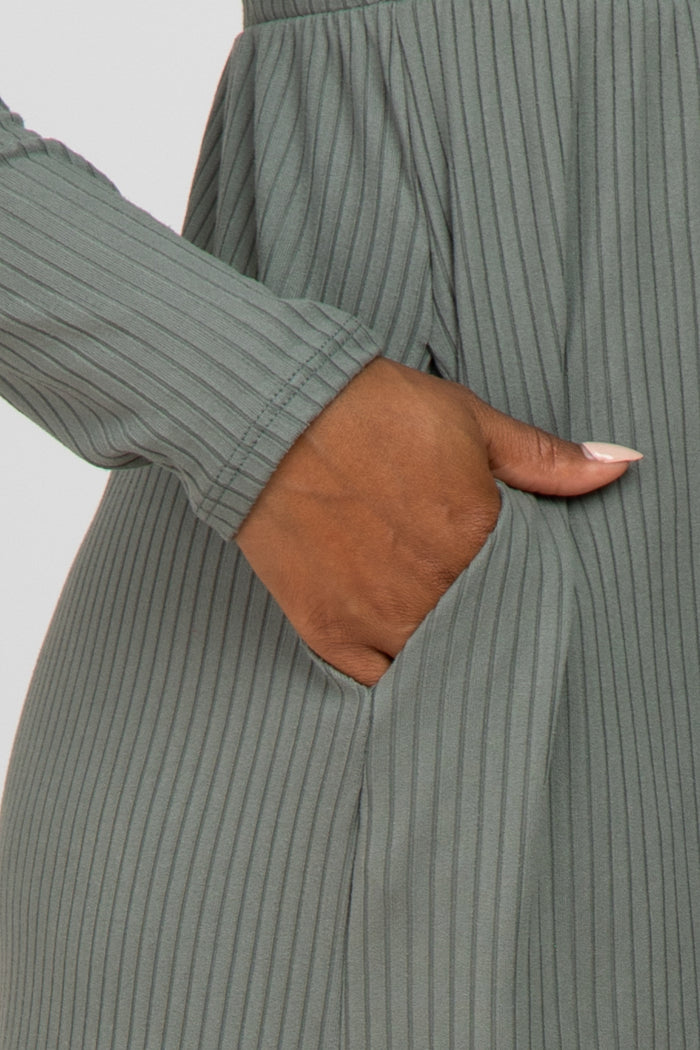 Close up of a person's hand in the side pocket of a sage green ribbed knit dress