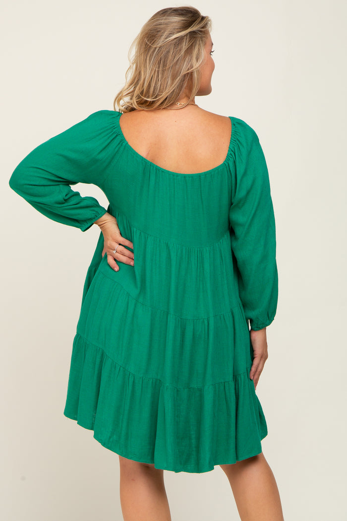 woman wearing a green tiered maternity dress with a scoop back and long sleeves, showing a relaxed fit
