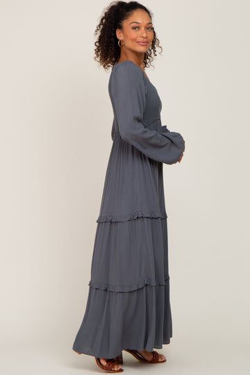 woman wearing a charcoal grey long sleeve tiered maxi dress with smocked bodice and ruffled details