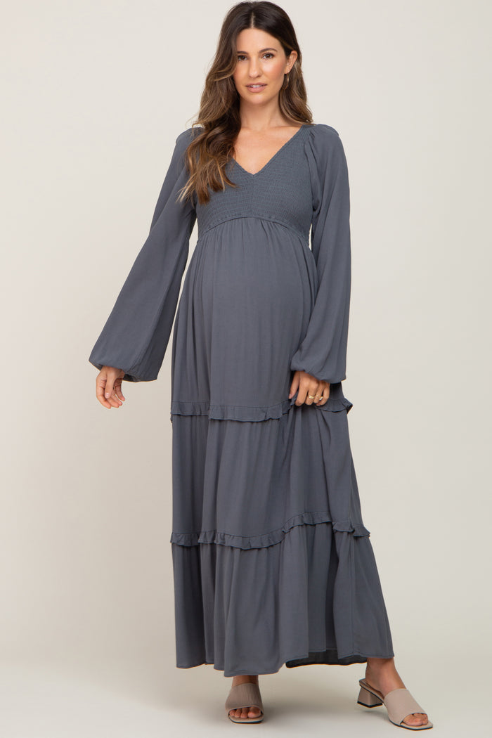 Pregnant woman wearing a charcoal grey long sleeve tiered maternity maxi dress with smocked bodice