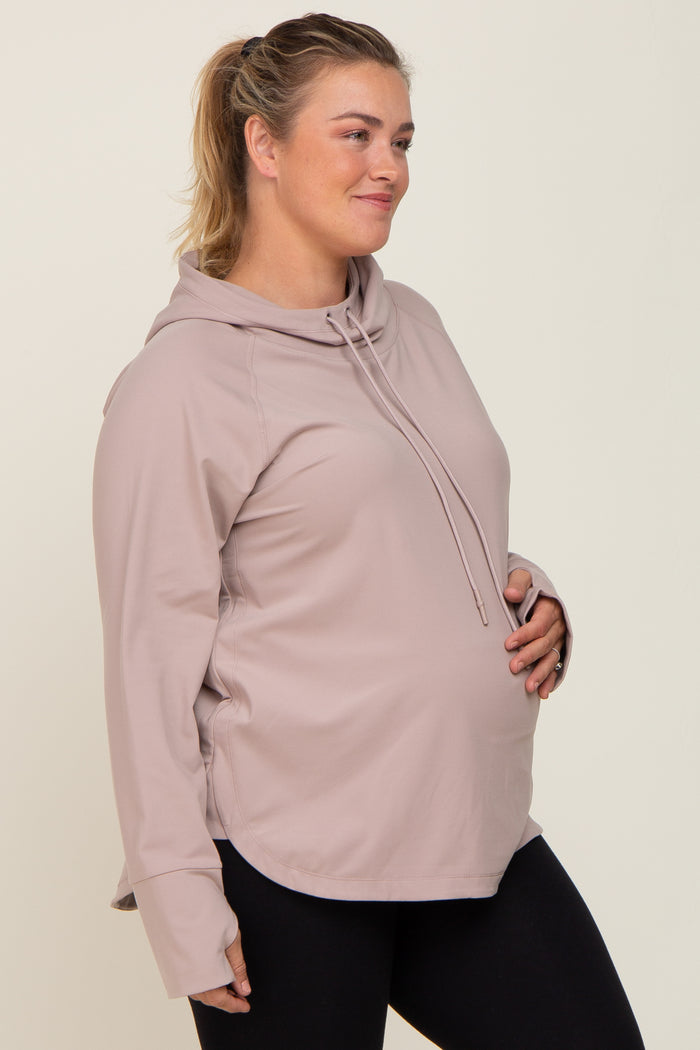 pregnant woman wearing a mauve maternity hoodie and black leggings holding her baby bump