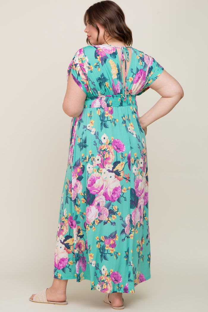 Woman wearing a mint green floral maxi dress with pink and purple flowers and a smocked waist
