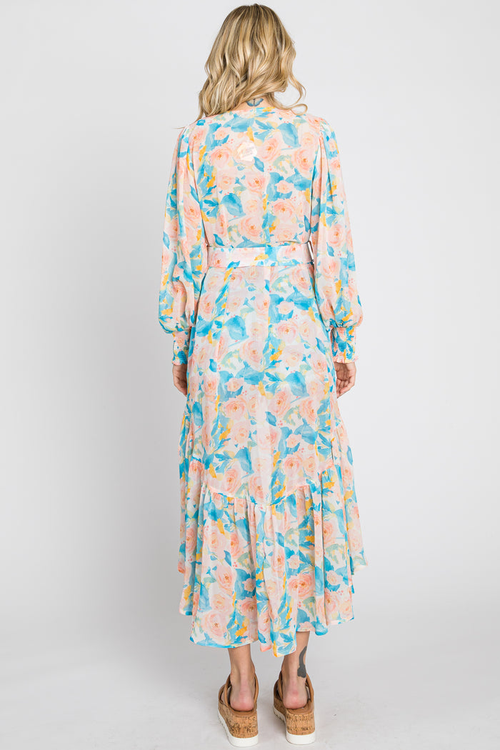 Back view of a woman wearing a long sleeve floral maxi dress with a belted waist and ruffled hem